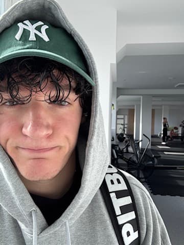 Kamil in a hoodie and cap at the gym